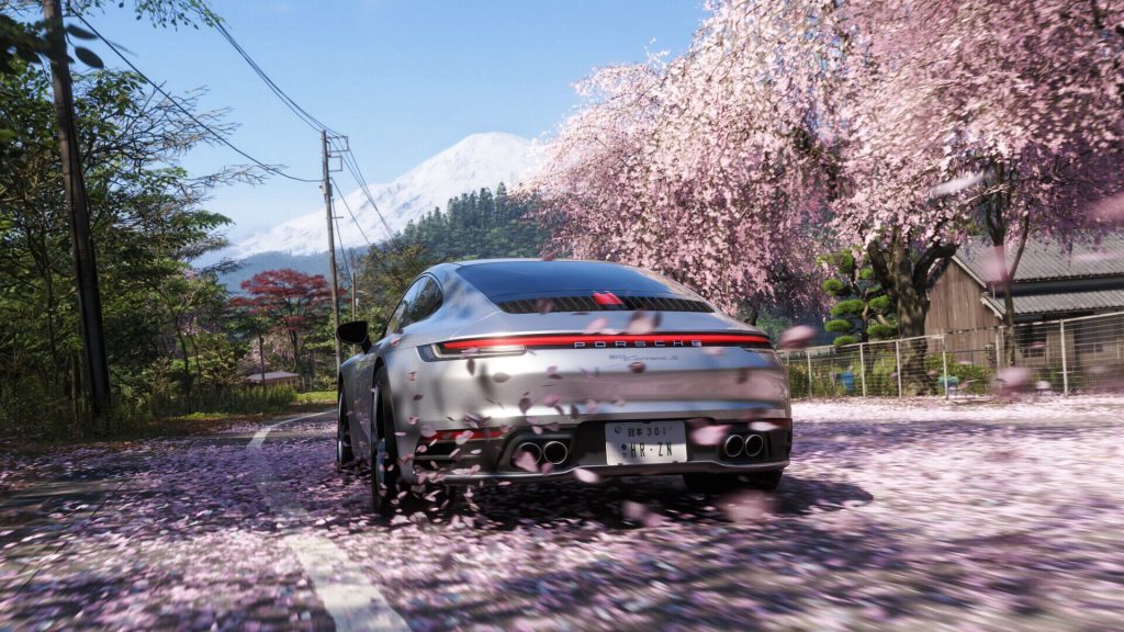 Une voiture de sport sous des cerisiers en fleurs, sur une route japonaise