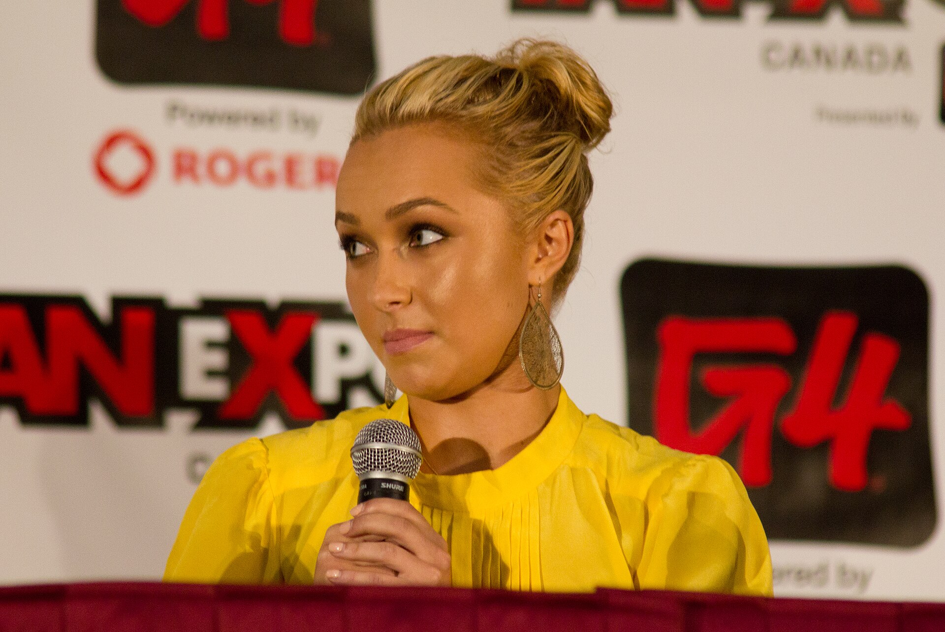 Hayden Panettiere, micro en main lors d'un panel a la Fan Expo Canada en 2011, devant les panneaux de l evenement