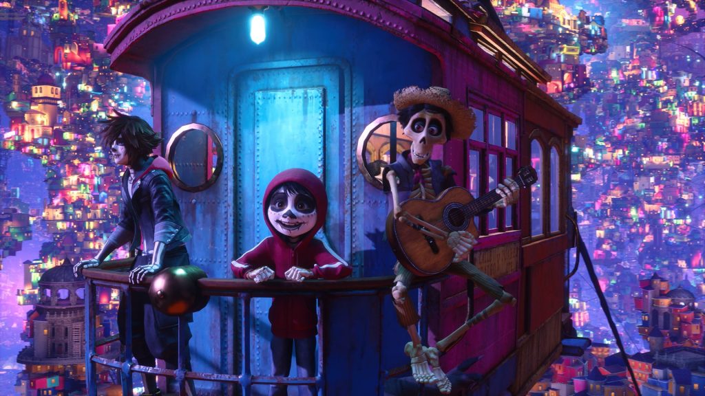 Sora, Miguel dans son sweat rouge et Hector avec sa guitare et son chapeau de paille, sur la plateforme d un funiculaire au-dessus de la cite des morts