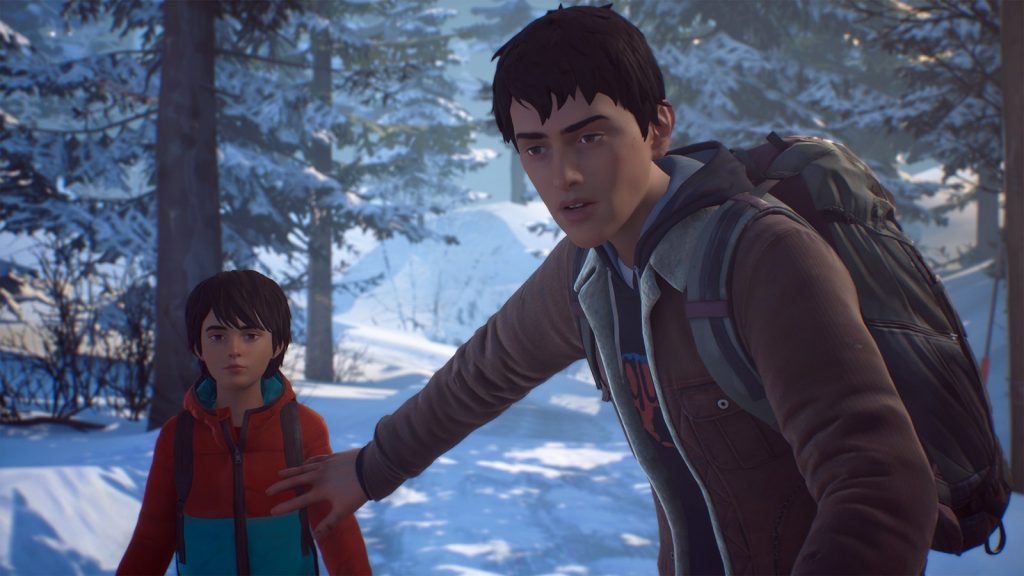 Sean Diaz, sac au dos, tend la main en arrière vers son petit frère Daniel dans une forêt de pins enneigée