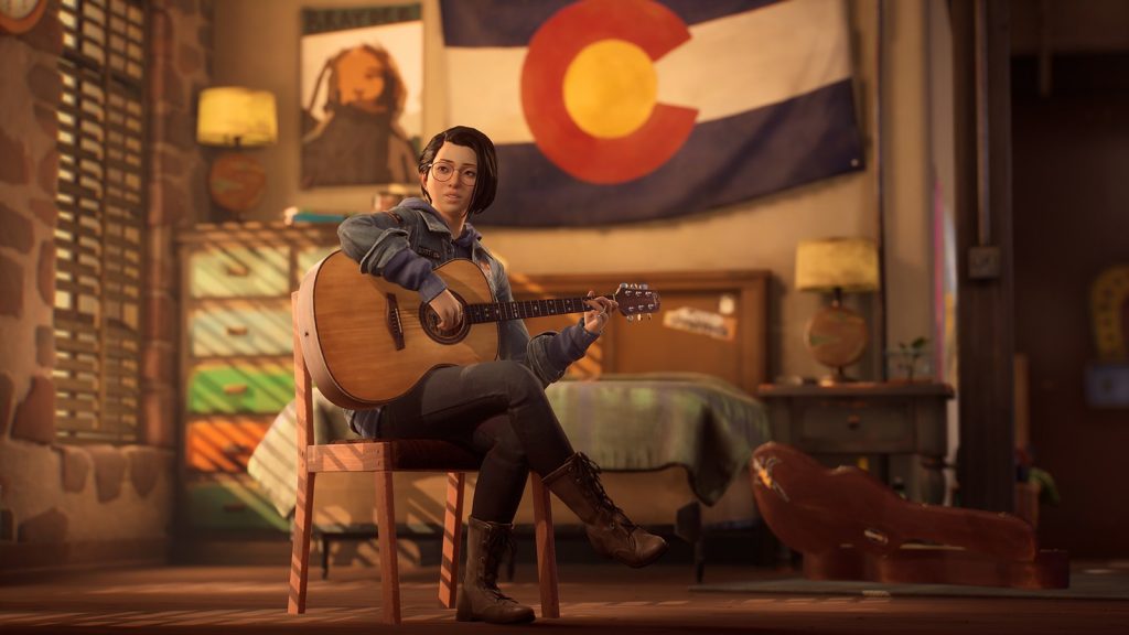Alex Chen assise sur une chaise en bois joue de la guitare acoustique dans une chambre, un drapeau du Colorado accroché au mur derrière elle
