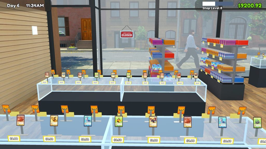 Intérieur aménagé d'une boutique dans TCG Card Shop Simulator, vitrines et présentoirs alignés devant une vitrine donnant sur la rue