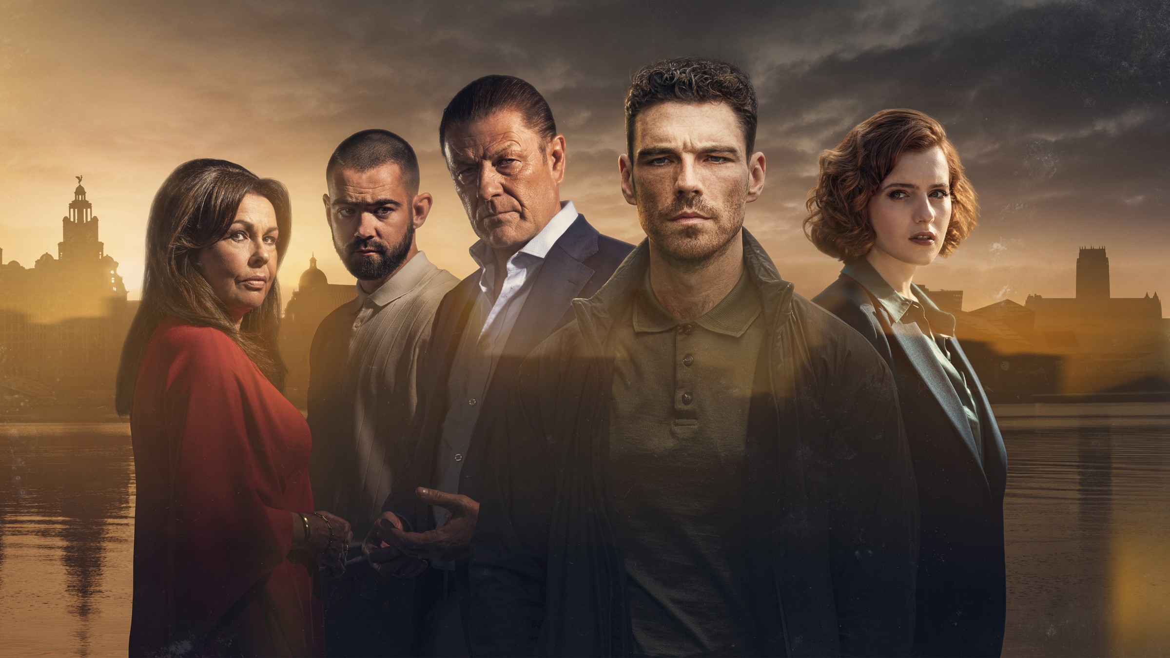 Sean Bean, au milieu de la distribution de This City Is Ours, devant les quais de Liverpool au coucher du soleil.