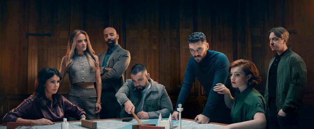 Des membres du clan réunis autour d’une grande table, dans une salle aux murs de bois sombre.