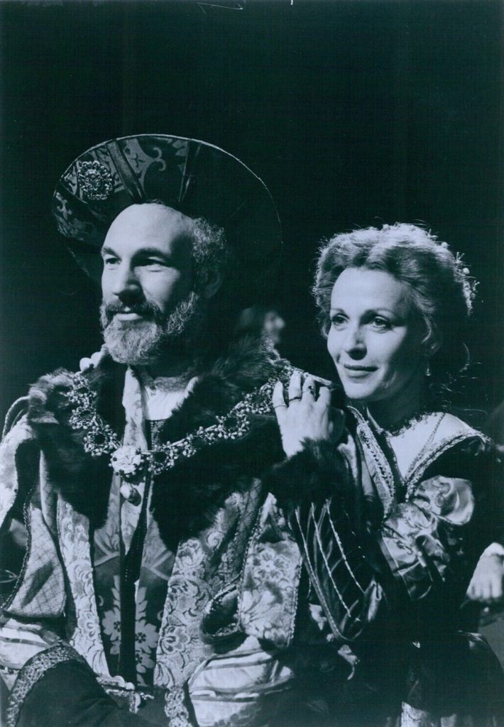 Photo en noir et blanc d'un homme barbu coiffé d'une couronne, en costume de cour brodé, à côté d'une femme en robe claire.