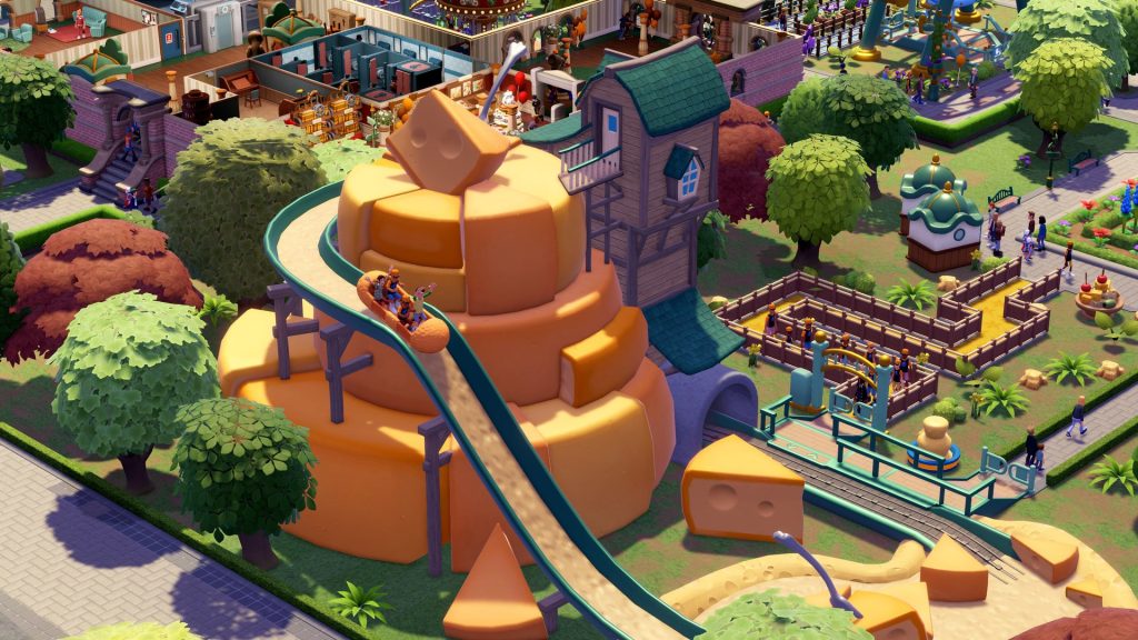 Un manège en forme de gâteau orange géant, avec un toboggan qui descend sa paroi, au milieu d'un décor de fromages.